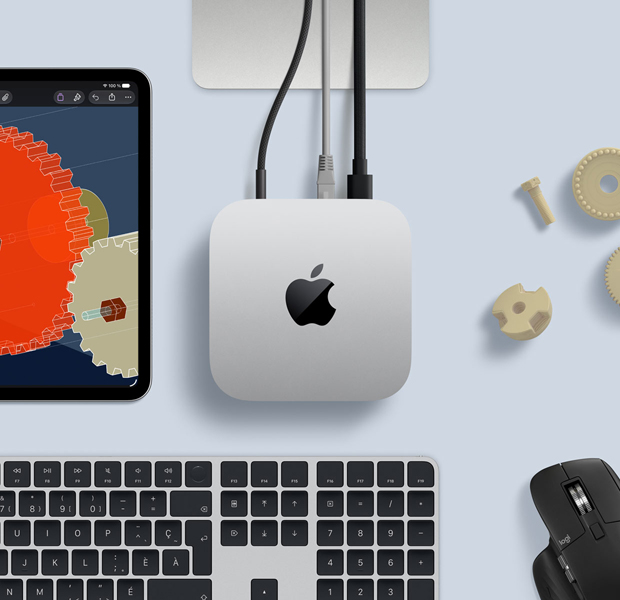 iPad affichant des objets STIM détaillés, Mac mini au centre avec un câble d’alimentation branché, support du Studio Display partiellement visible, connecté via USB-C, Magic Keyboard avec Touch ID, et souris Logitech
