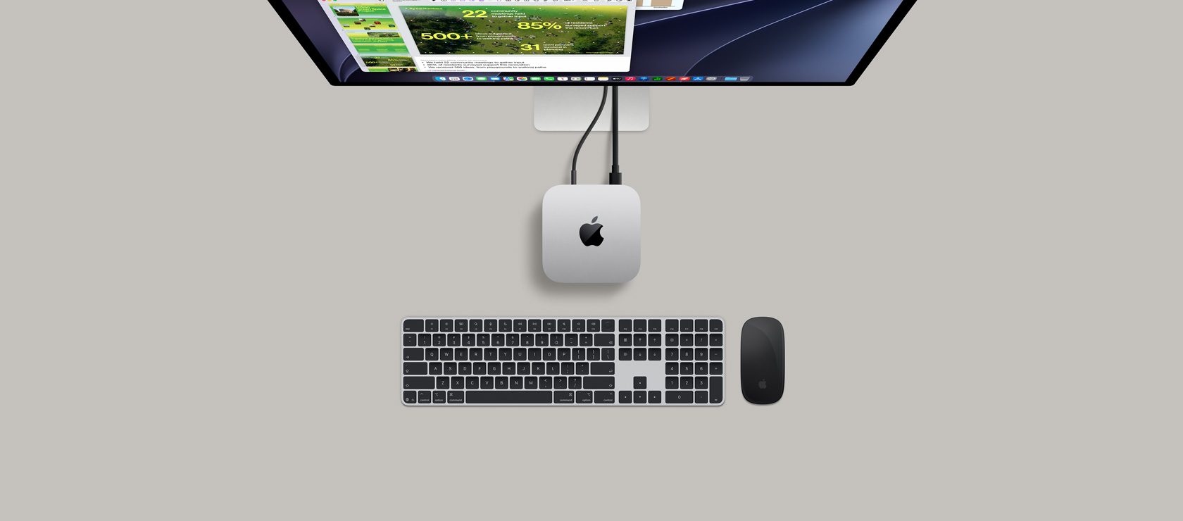 Widok z góry na Maca mini, obudowa z aluminium w kolorze srebrnym, zaokrąglone rogi, czarne błyszczące logo Apple pośrodku, podłączony przewodem, częściowo widoczny monitor Studio Display, słuchawki AirPods 4, otwarte, karty kolorów Pantone oraz czerwona klawiatura i mysz Logitech