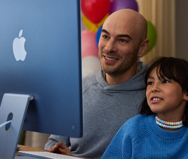 Orang dewasa dan anak keduanya antusias dengan konten di iMac, biru