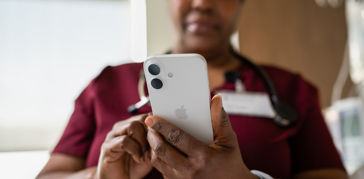 Een verpleegster in rode kleding kijkt naar haar iPhone.