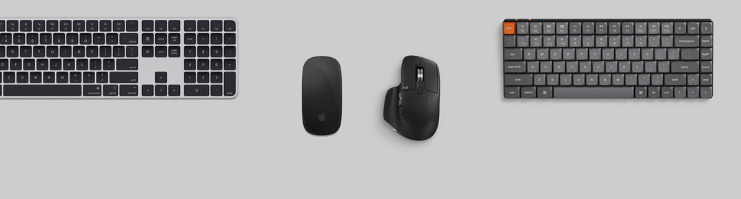 Sidabro spalvos „Mac mini“ ant stalo su monitoriumi, belaidėmis klaviatūromis, belaidėmis pelėmis, žaidimų valdikliu ir „AirPods Max“ vaizdas iš viršaus.