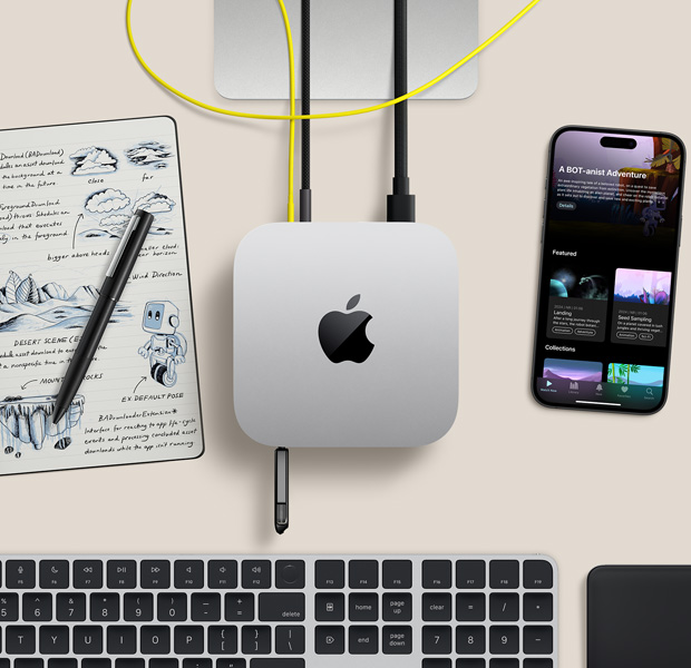 Sidabrinio „Mac mini“ su laidais ir „flash“ atmintine, prijungtais prie prievadų, ant darbo stalo su belaidžio ryšio klaviatūra, manipuliatoriumi, „iPhone“ ir užrašų knygele, vaizdas iš viršaus